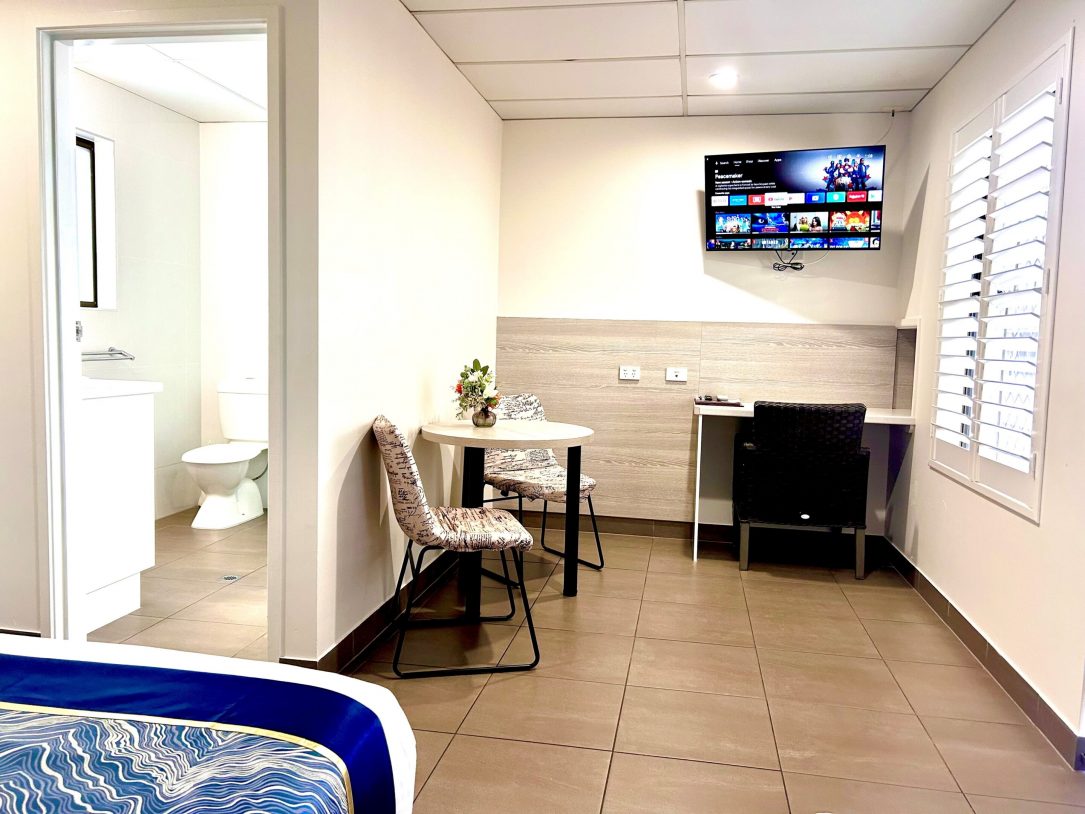 Twin Room With TV On And Visible Bathroom Entrance — Chalet Motor Inn In Bundaberg West, QLD